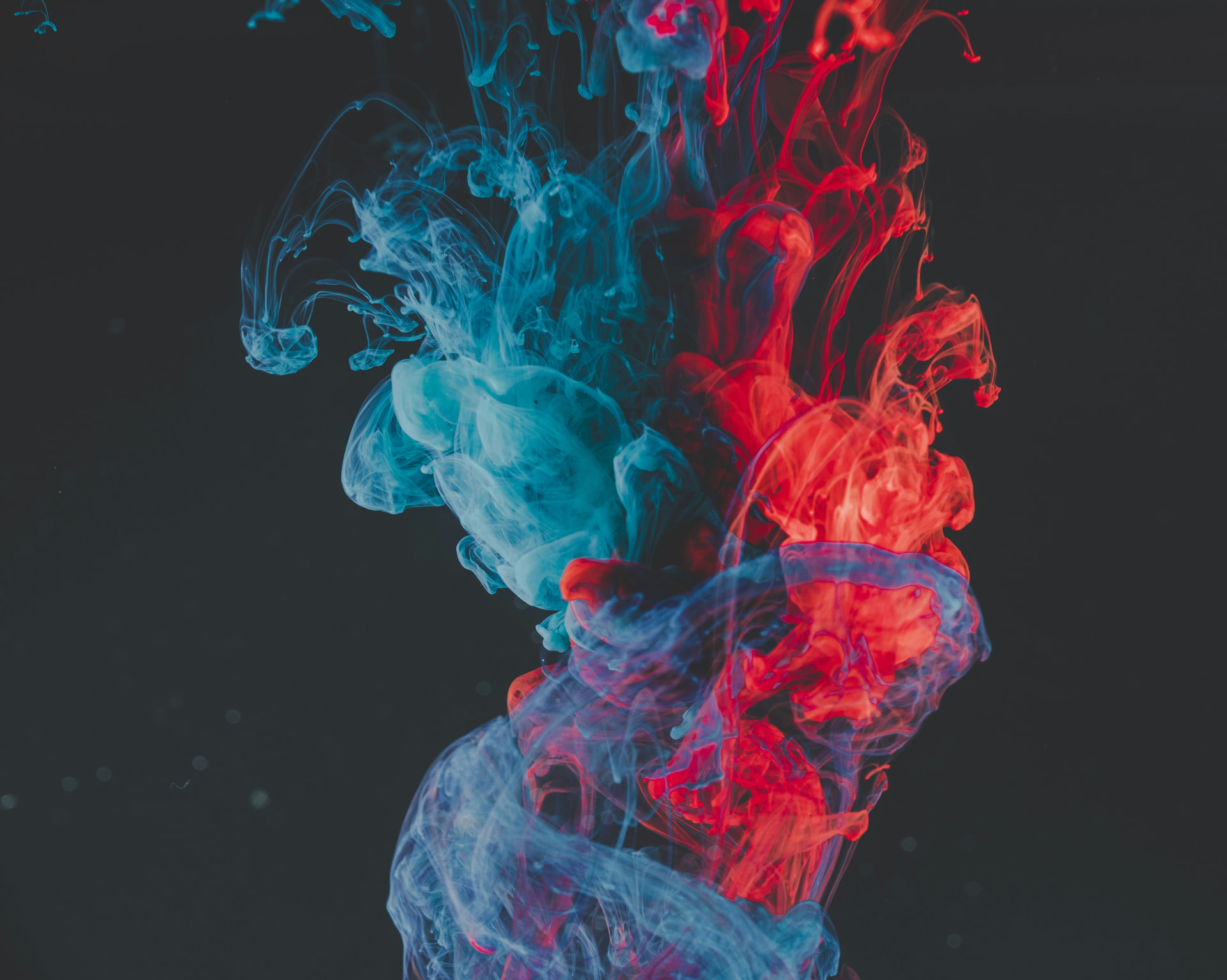 Blue and red ink swirling together against a dark background